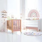 Habitación infantil con cuna y cómoda en rosa y madera