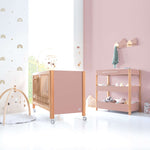 Habitación de bebé con cuna y cómoda-cambiador en rosa y madera