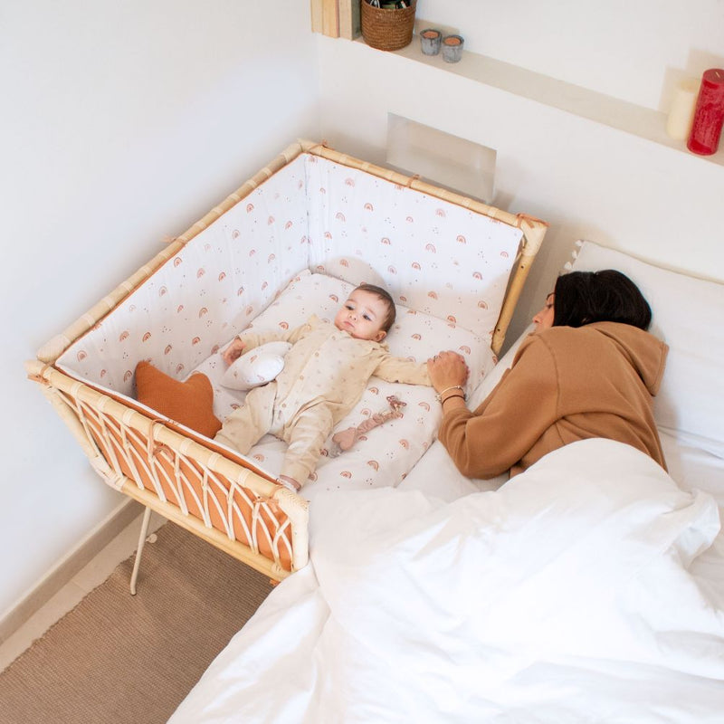 Minicuna de ratán pegada a la cama para colecho