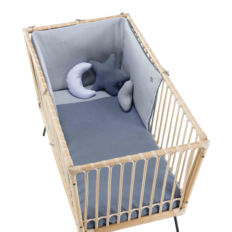 Cuna de bebé en ratán con ropa de cuna en color azul marino